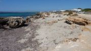 Zona de arena y rocas con el restaurante al fondo