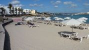 Playa en Es Pujols con sombrillas blancas y tumbonas color crema