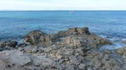 Zona rocosa y al fondo un velero