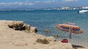 Sombrilla en primer plano, al fondo la isla de Ibiza