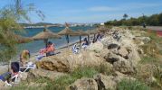 playa muy estrecha con sombrillas y hamacas 