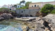 la playa esta limitada entre dos zona rocosas y un muro roto de piedra