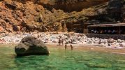 dos turistas entrando al agua y los dems tomando el sol