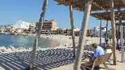 hombre ecriviendo sentado en un banco cerca de la playa