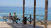 un banco con dos personas sentadas disdfrutando de paisaje a la sombra