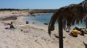 playa con bastante arena y un par de sombrillas